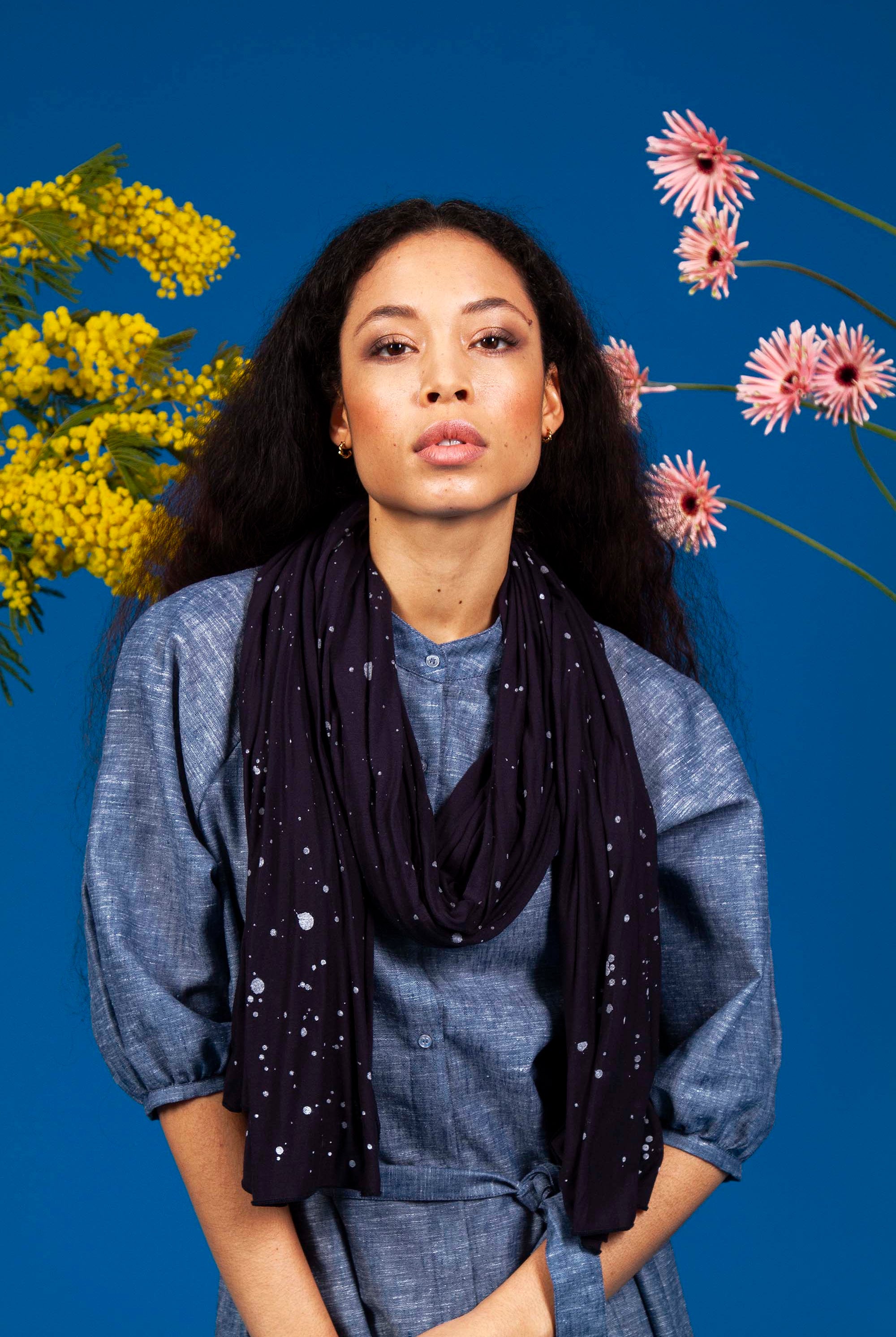 jeune femme métisse sur fond fleuri portant un foulard en modal matière durable
