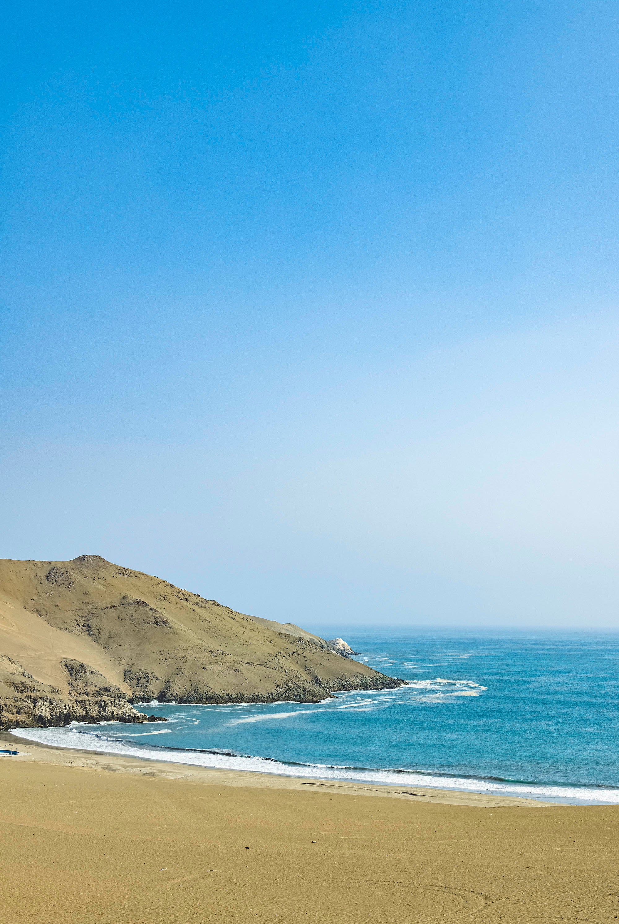 Plage au bord de l'océan atlantique au Pérou avec dunes visibles sur la gauche et temps ensoleillé