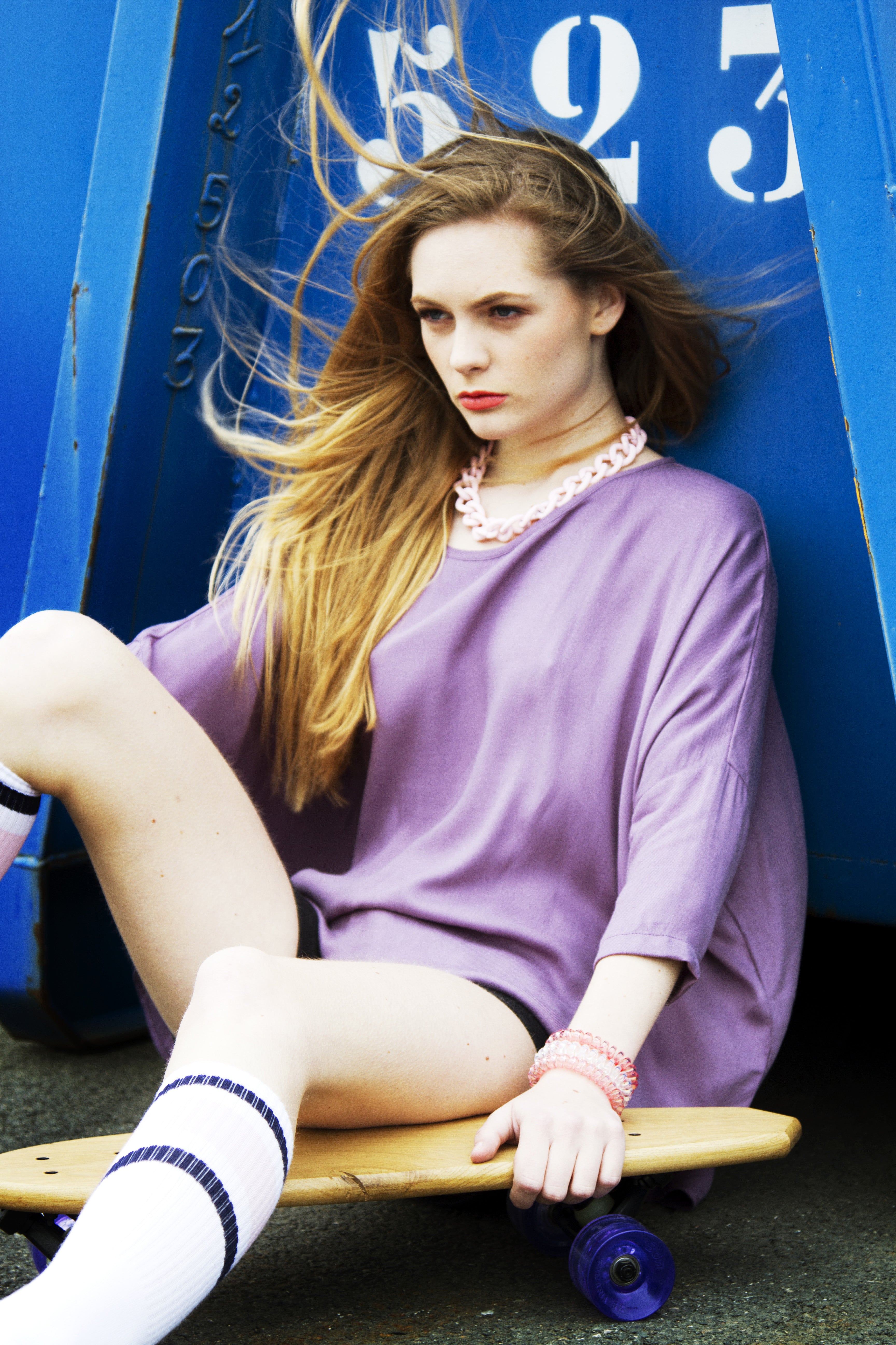 Jeune femme blonde assise avec un skateboard et chaussettes fantaisies