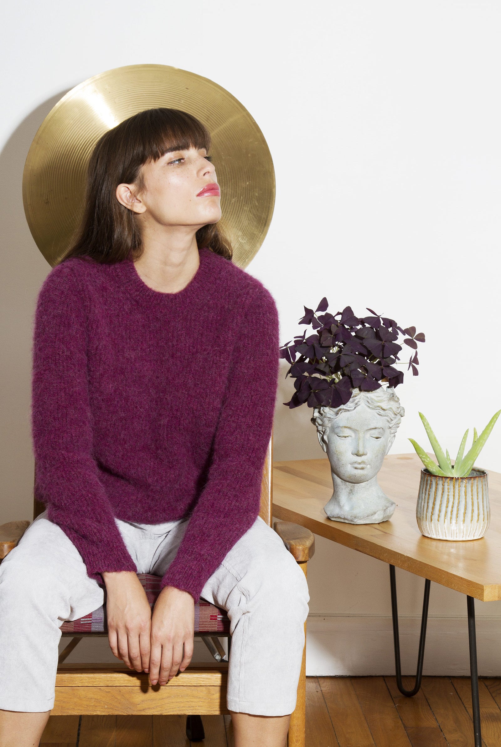 Femme brune à frange élégante look parisienne pull violet pantalon blanc