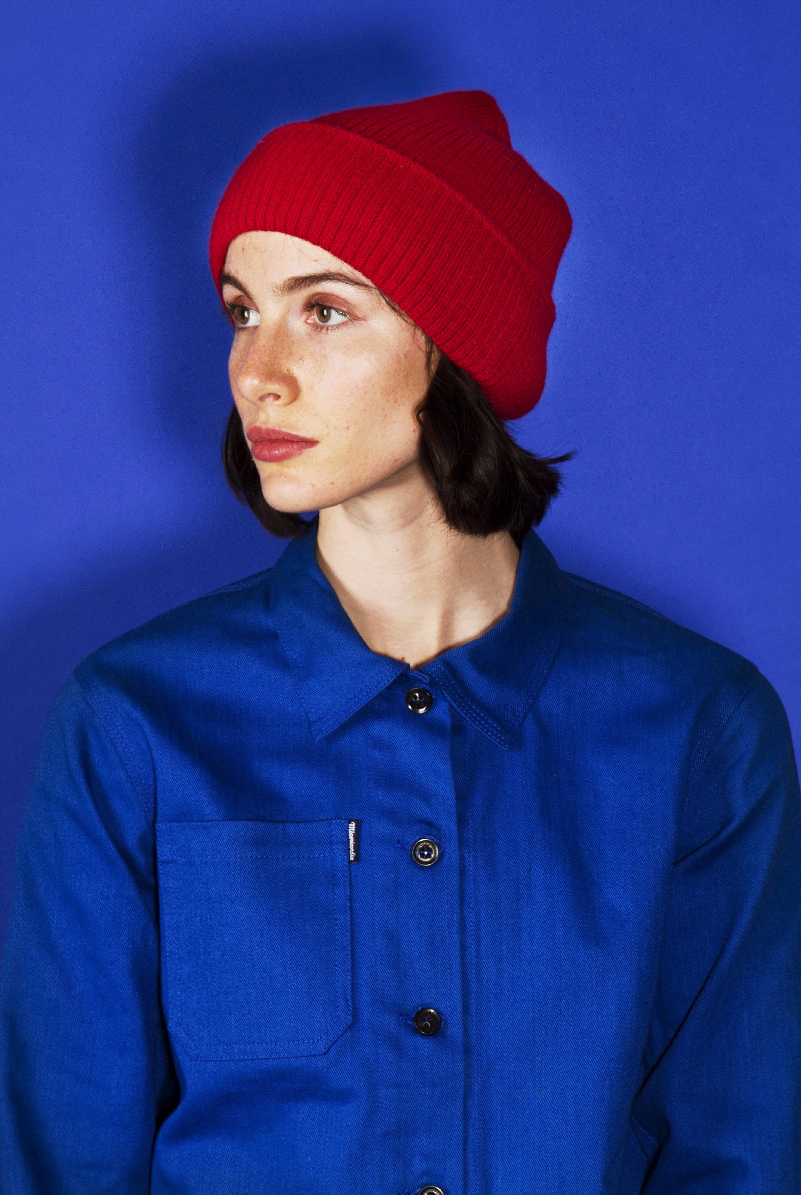 Jeune femme brune regardant de côté, contraste de couleur rouge et bleu, pièces iconiques