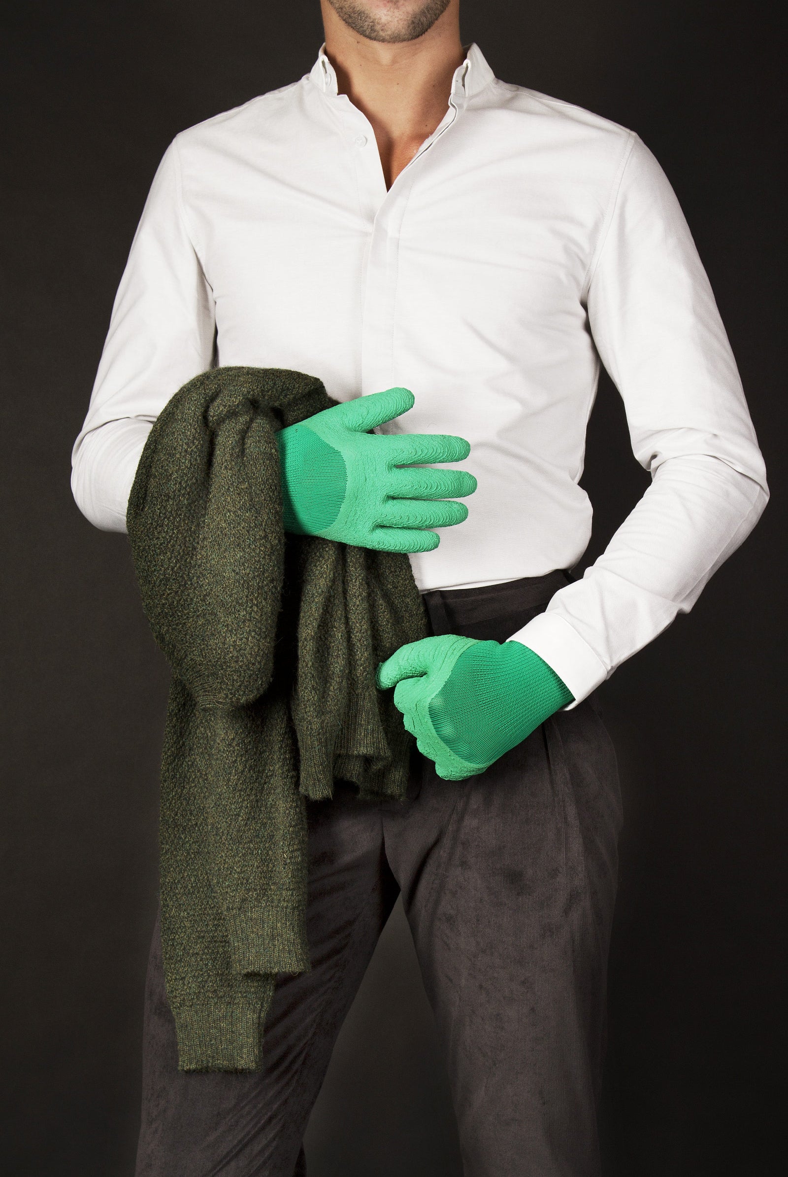 Style décalé homme en chemise blanche tenant un pull en alpaga avec des gants caoutchouc
