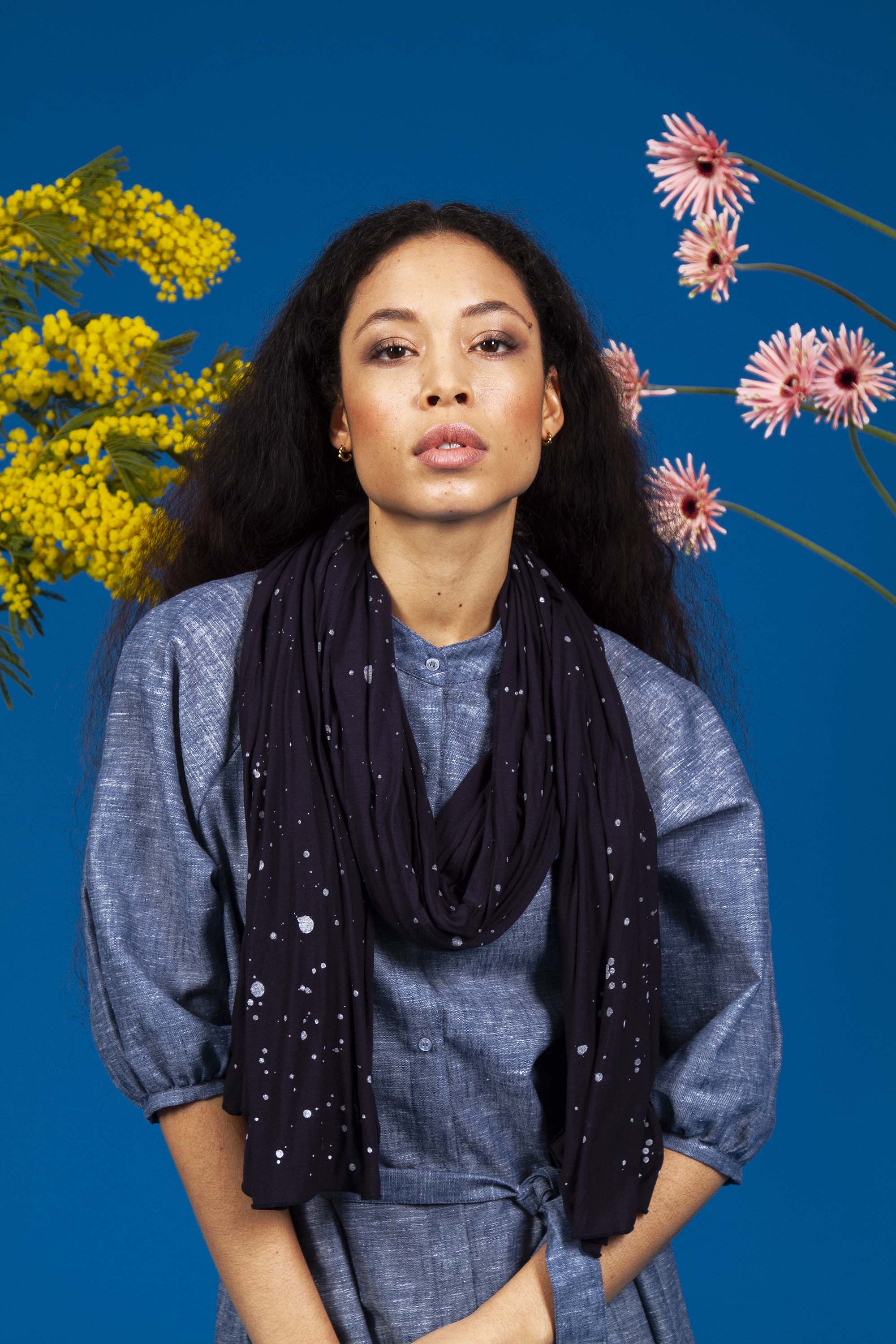 jeune femme métisse sur fond fleuri portant un foulard en modal matière durable