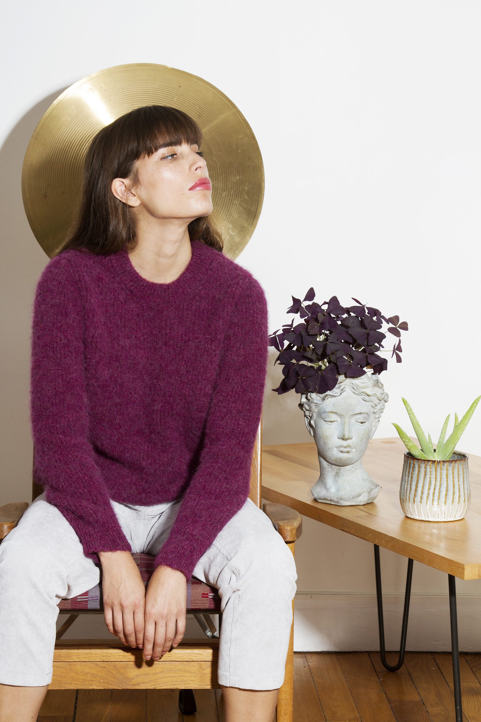 Femme brune à frange élégante look parisienne pull violet pantalon blanc