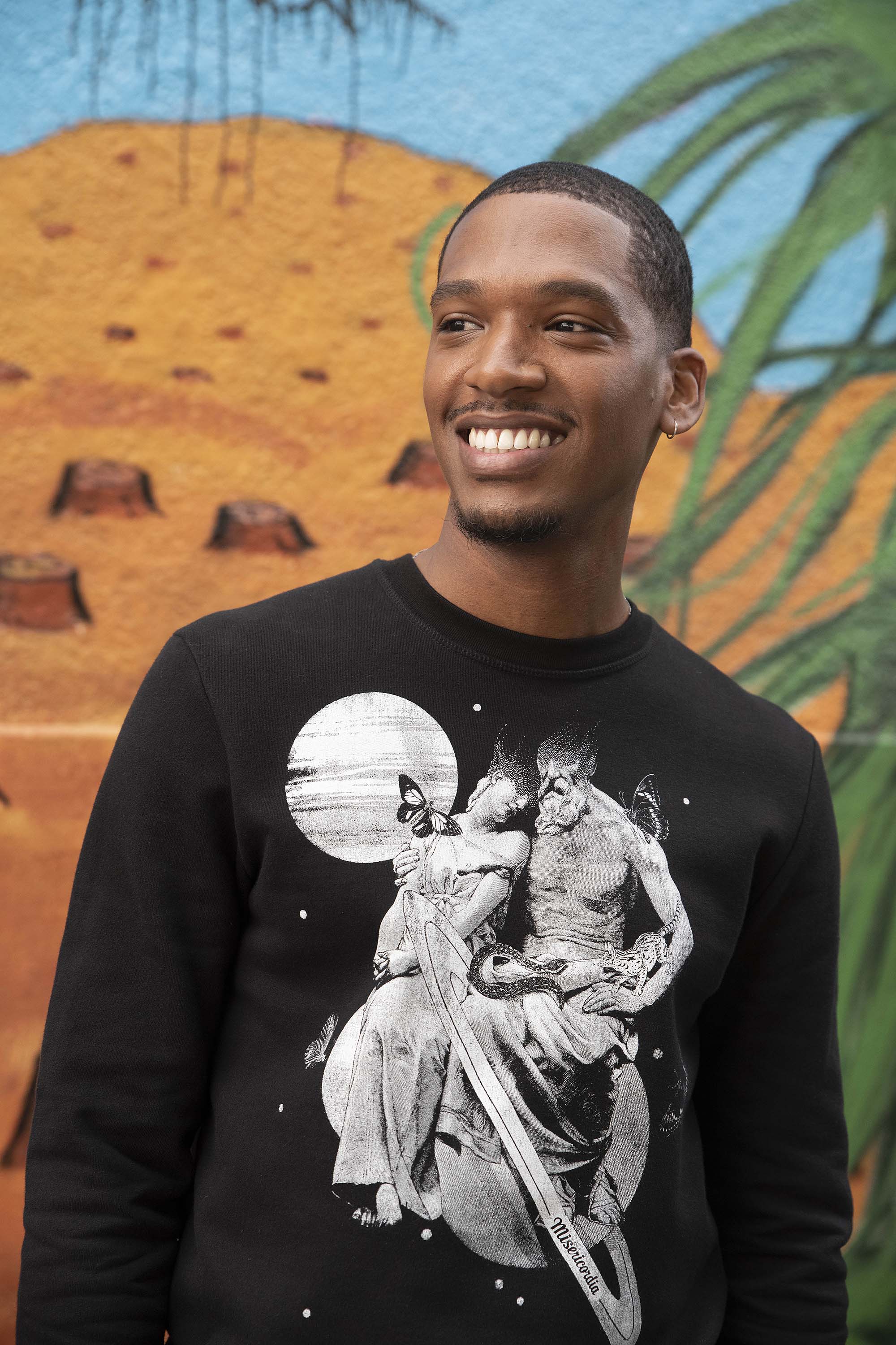 Jeune homme souriant style sport chic en sweat à motif noir et blanc, mode urbaine