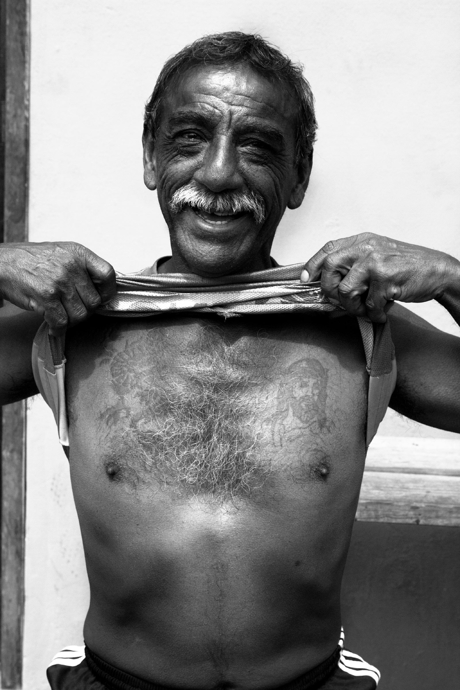 Homme péruvien soulevant son t-shirt pour montrer ses tatouages