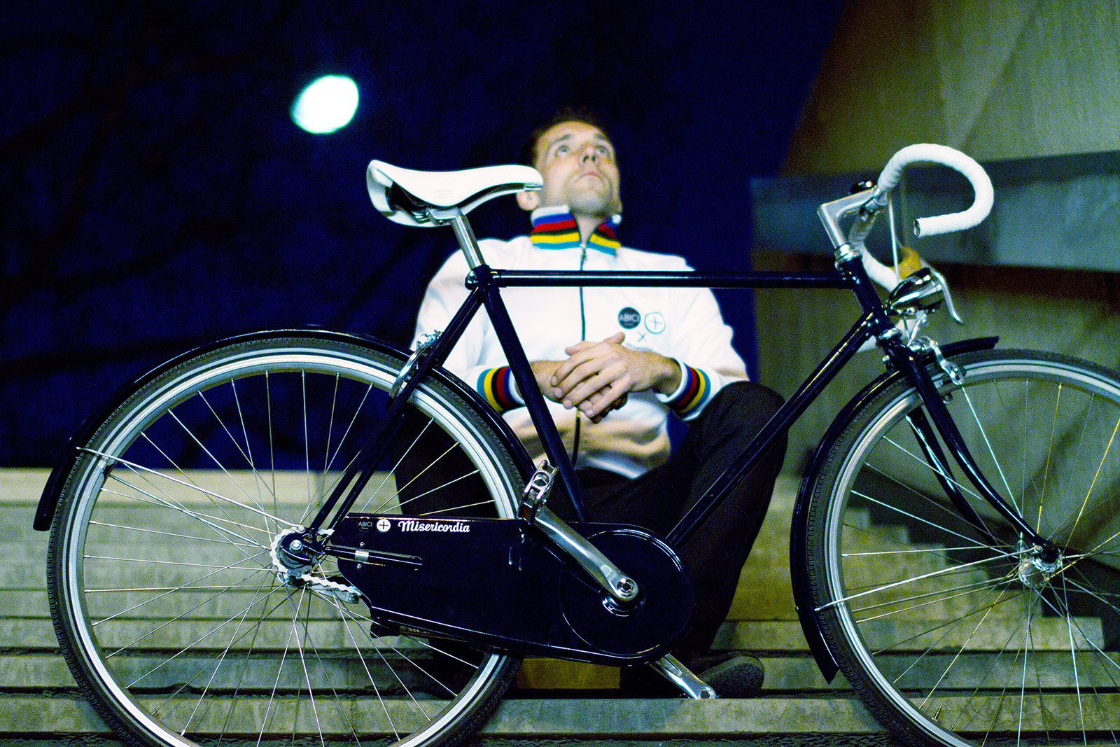 homme cycliste assis dans des marches avec son vélo ambiance urbaine underground photo de nuit 