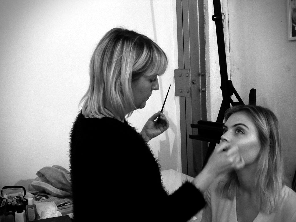 Maquilleuse préparant une mannequin pour le shooting photo de la dernière collection