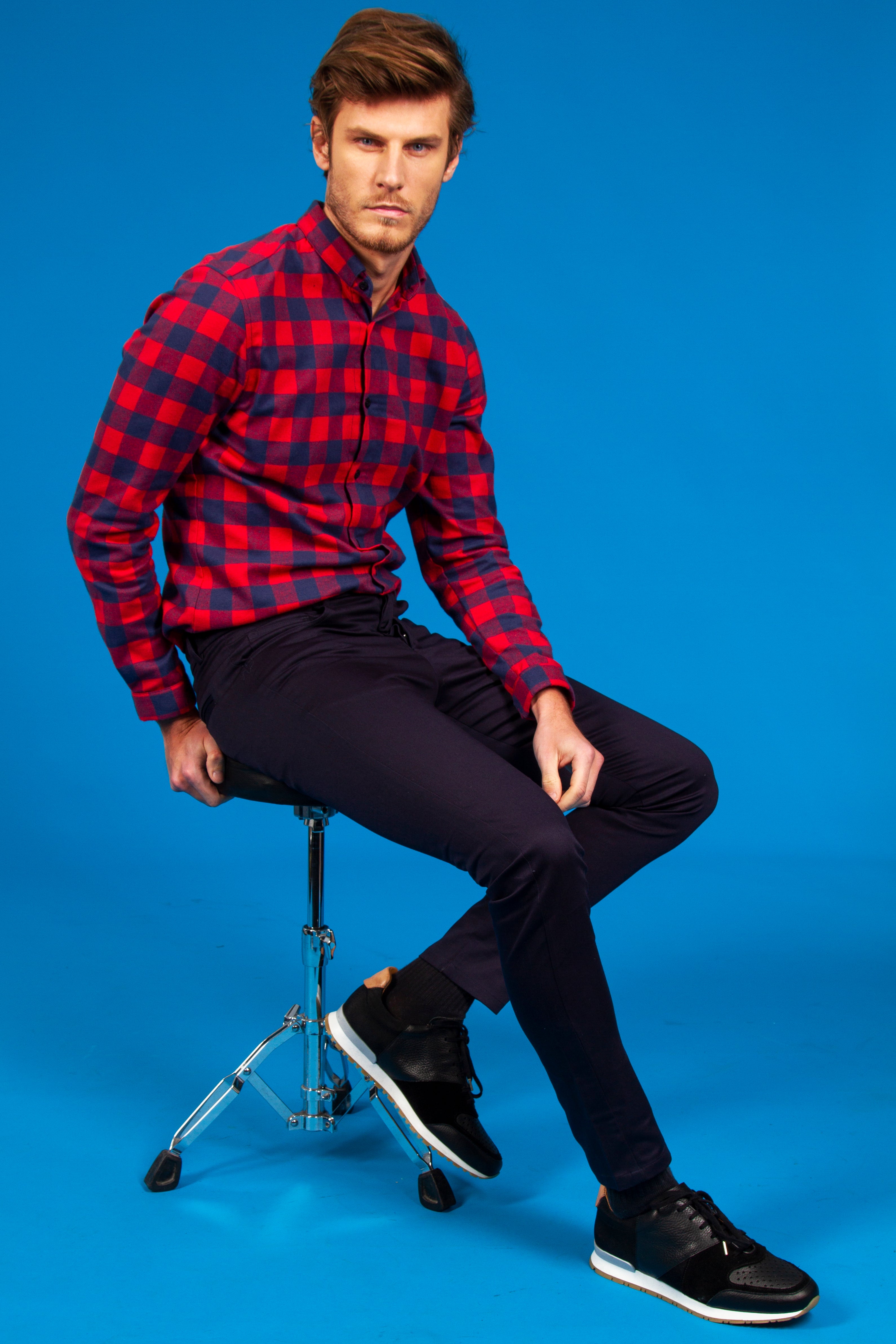 homme qui porte un pantalon et une chemise éthique et responsable assis sur un tabouret dans un studio photo à Paris